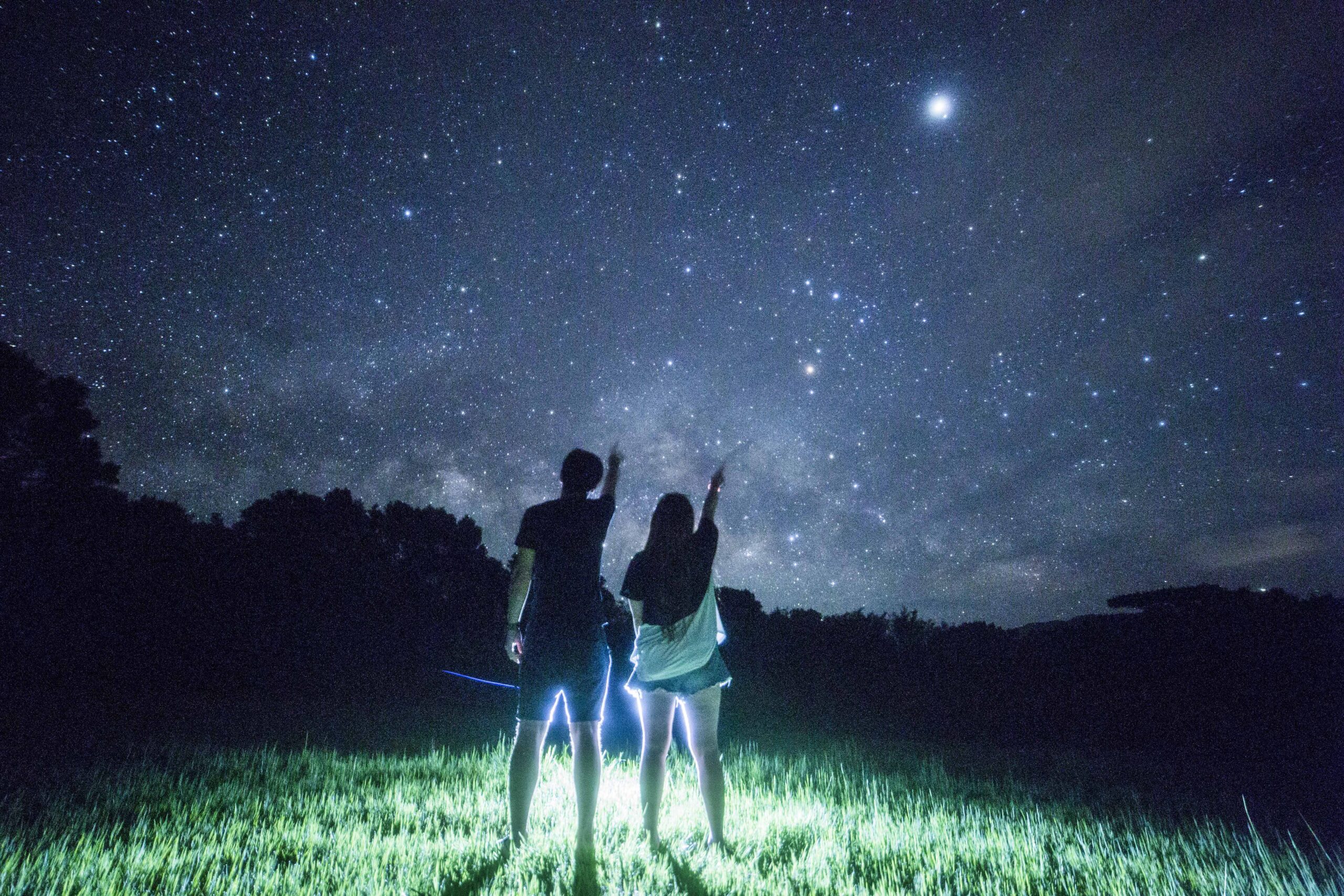 Couple looking up at the starry sky in a grass field at Nagareboshi no Oka, Ishigaki Island