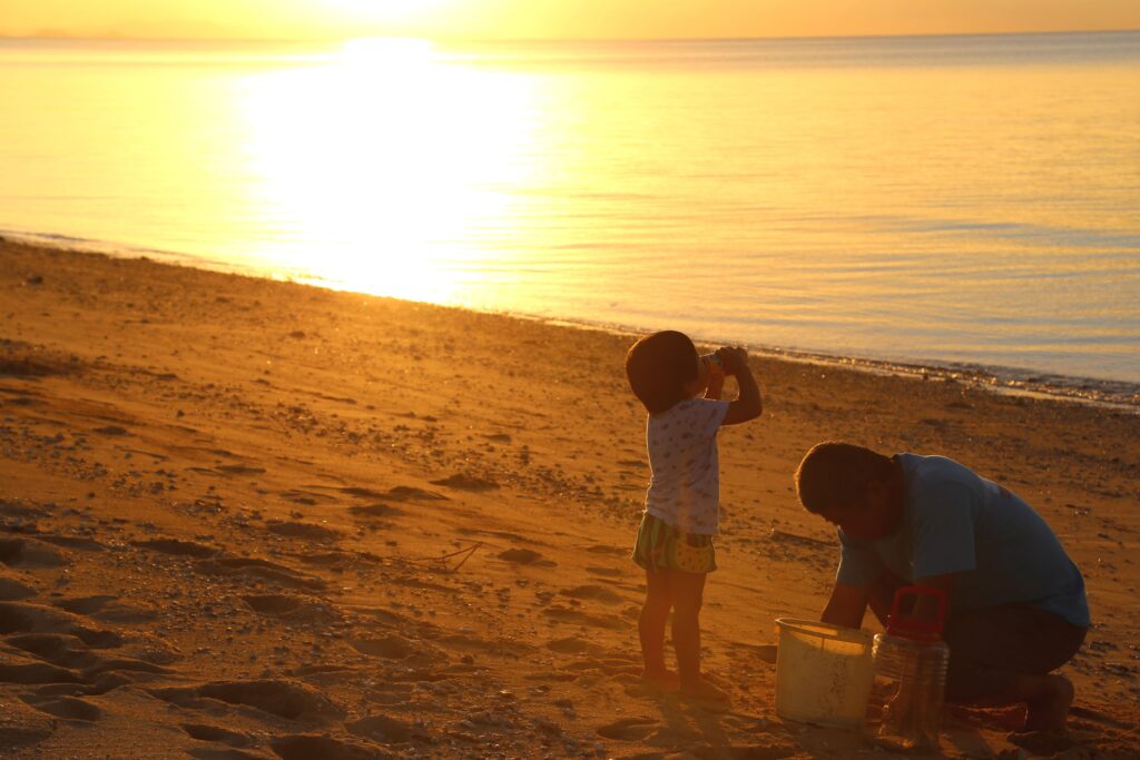 Family enjoying the sunset on Ishigaki Island beach — a peaceful scene before a stargazing tour at Nagareboshi Hill