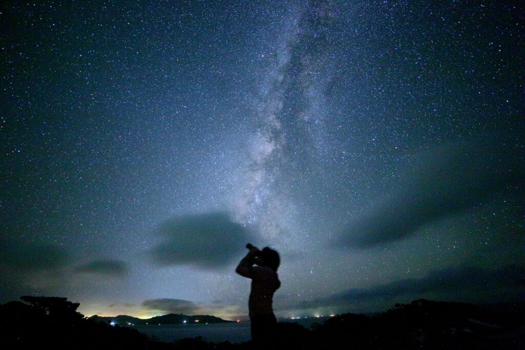 Person watching Milky Way through binoculars at Nagareboshi Hill, Hirakubo Peninsula, Ishigaki Island dark sky site