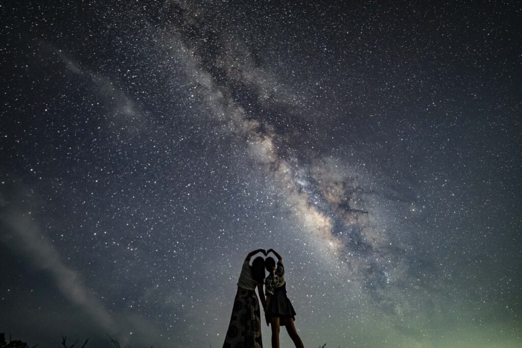 Women two heart pose milky way at Nagareboshi no Oka stargazing spot, Ishigaki Island